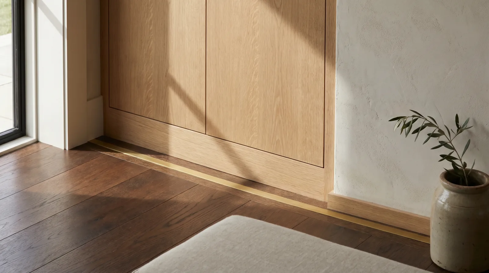 Interior architectural detail: quartersawn white oak built-in cabinet, brass floor inlay strip, and plaster wall, craftsmanship details from an Icon Projects custom home.